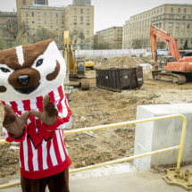 Bucky Badger in front of construction site.