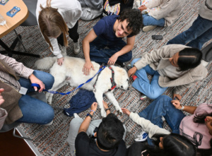 Several students petting beige dog