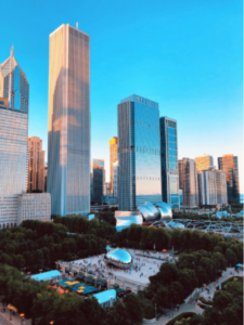 Aerial view of Chicago's Millennium Park with the reflective Cloud Gate sculpture and surrounding skyscrapers at sunset.