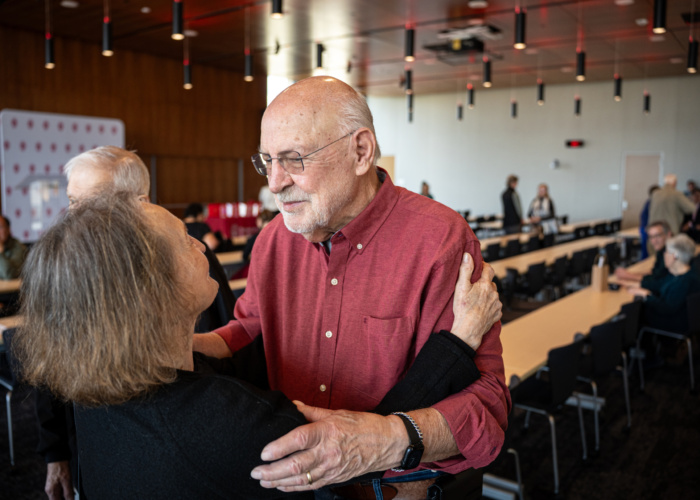 Award winner Prudence Dalrymple embraces an event attendee in a modern room.